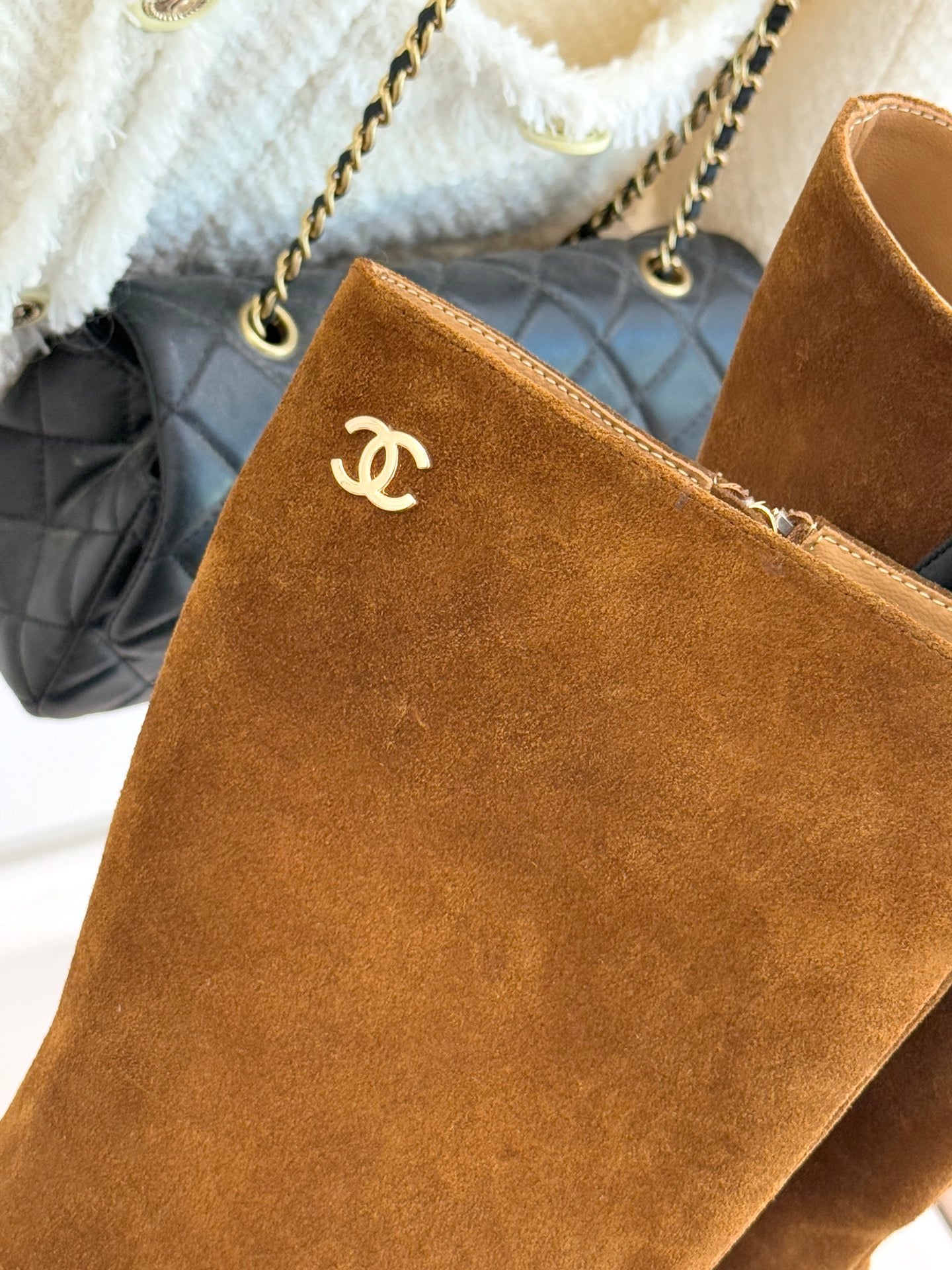 Tan suede tall boot with CC logo on cuff and side zipper pull
