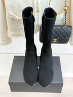 Pair of black suede tall boots with side zippers and block heels, front view on box