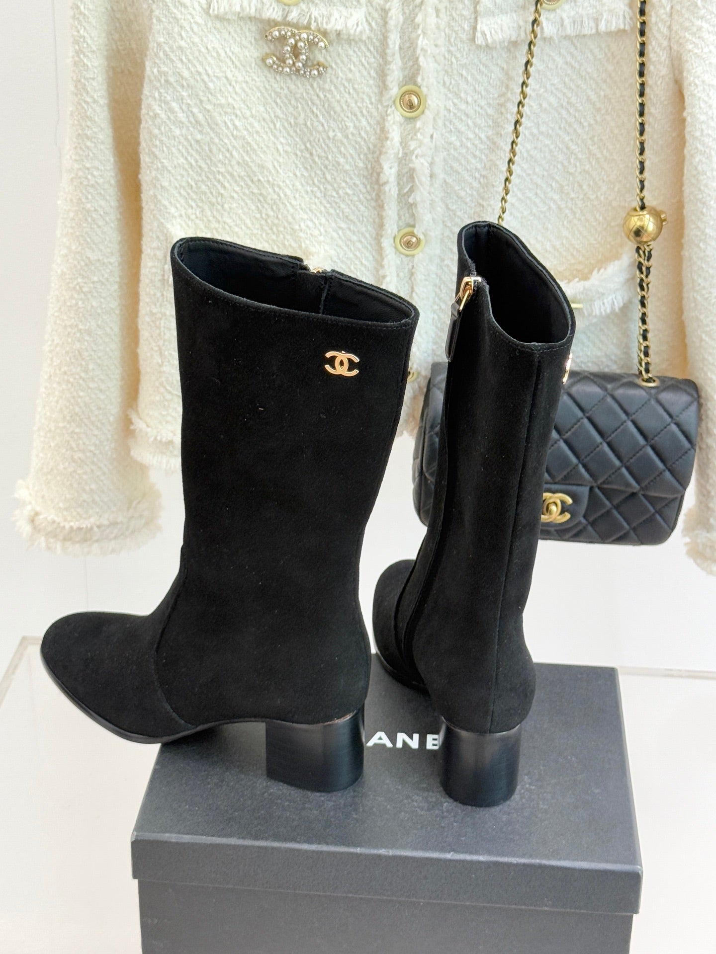 Black suede tall heeled boots with Chanel CC logos, side zippers, on display box