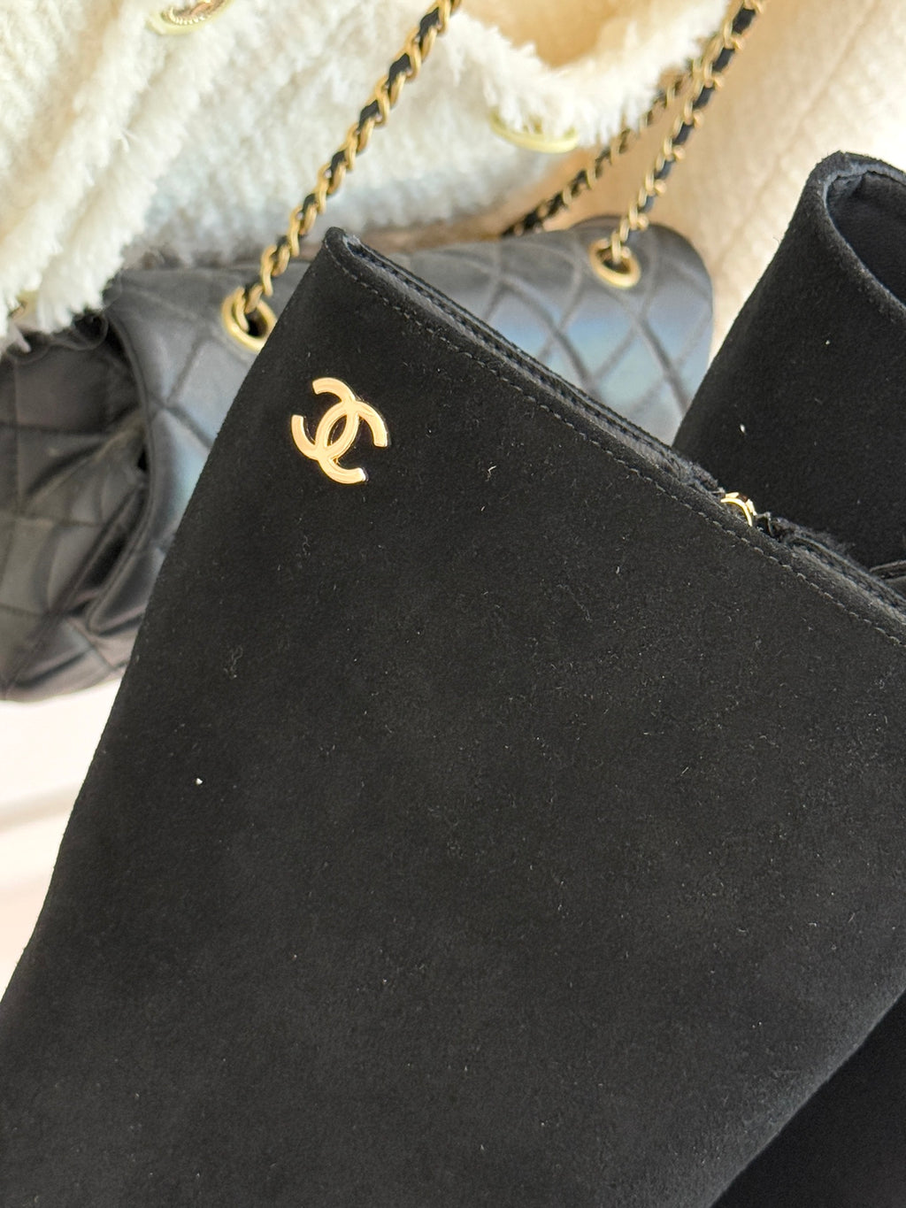 Close-up of black suede boot upper with Chanel CC emblem near ankle