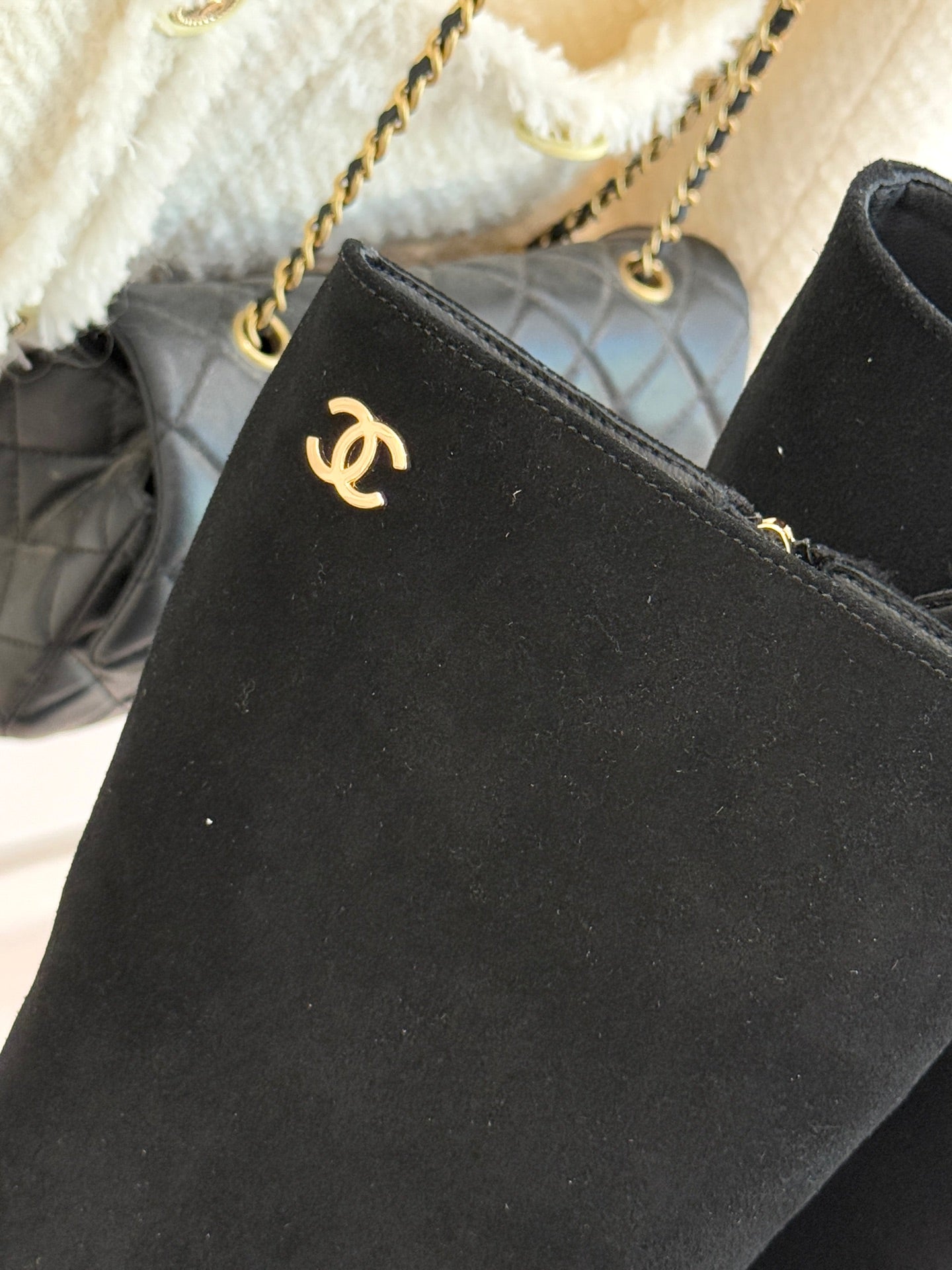 Close-up of black suede boot upper with Chanel CC emblem near ankle