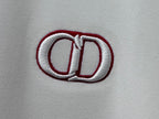 Close-up of white top with red-trimmed CD logo embroidery