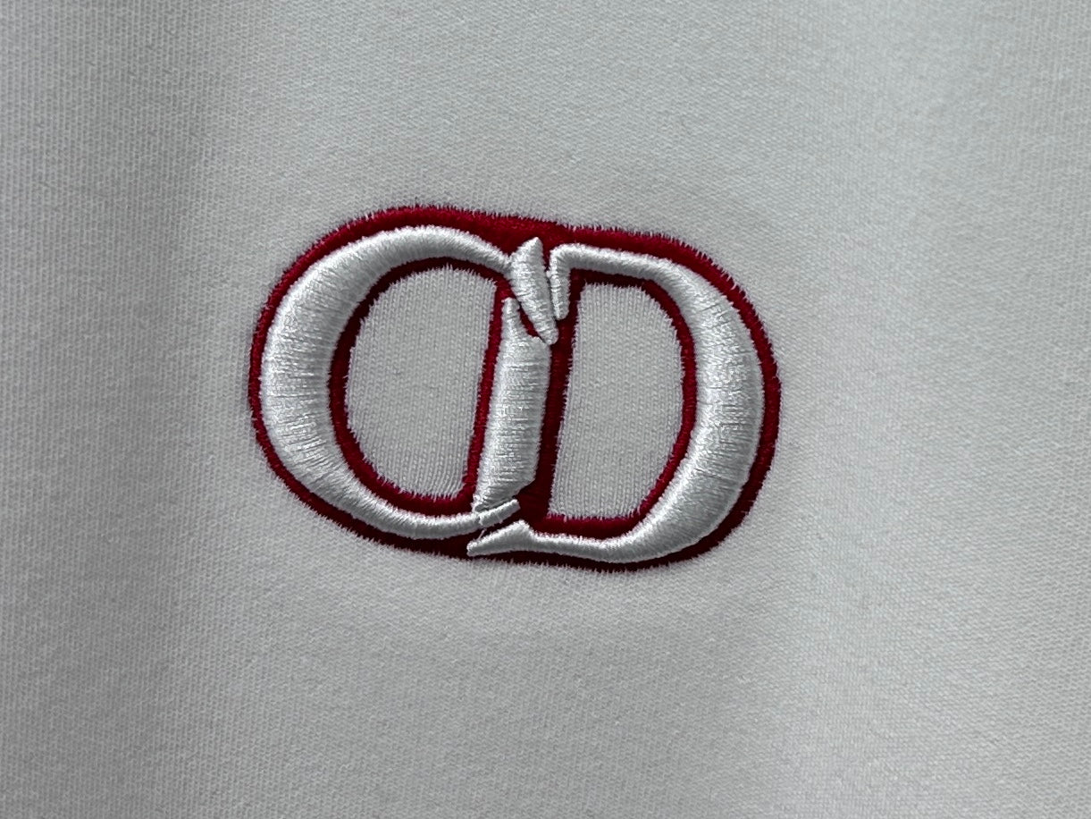 Close-up of white top with red-trimmed CD logo embroidery