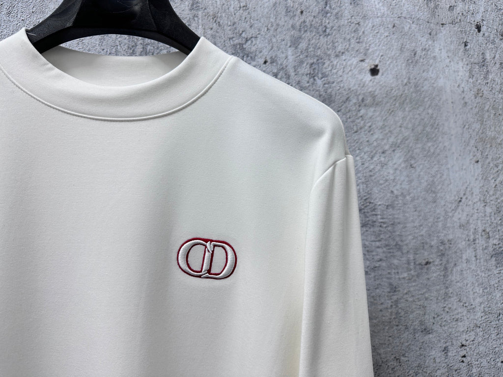 White crewneck top with red CD logo patch at left chest