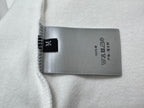 White top with gray fabric care label and black brand tag at hem