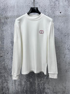 White long-sleeve crewneck top with small red-and-black CD logo on chest