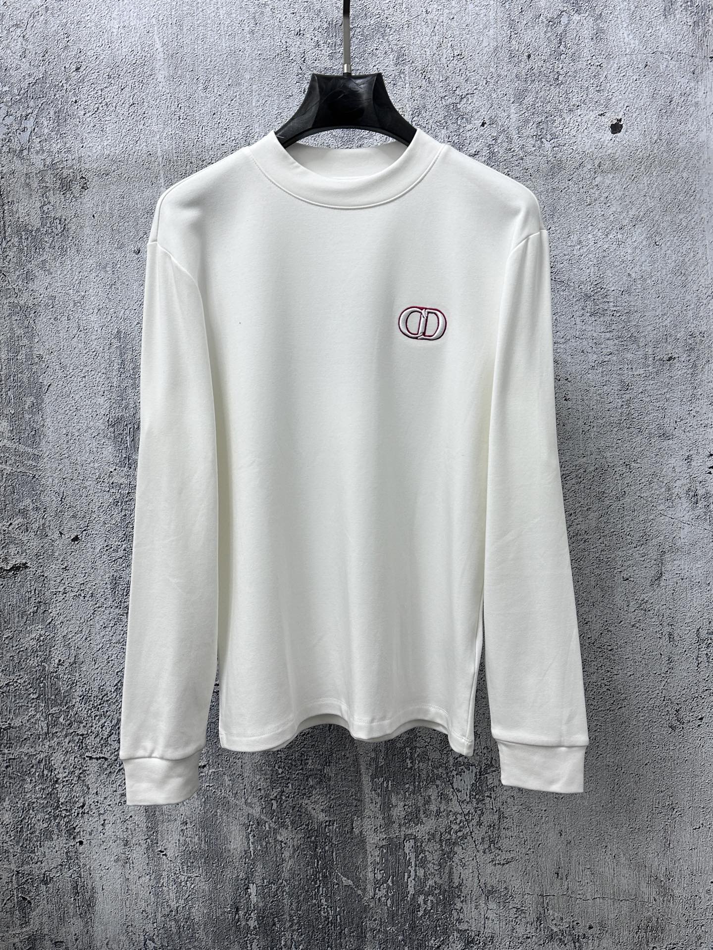 White long-sleeve crewneck top with small red-and-black CD logo on chest