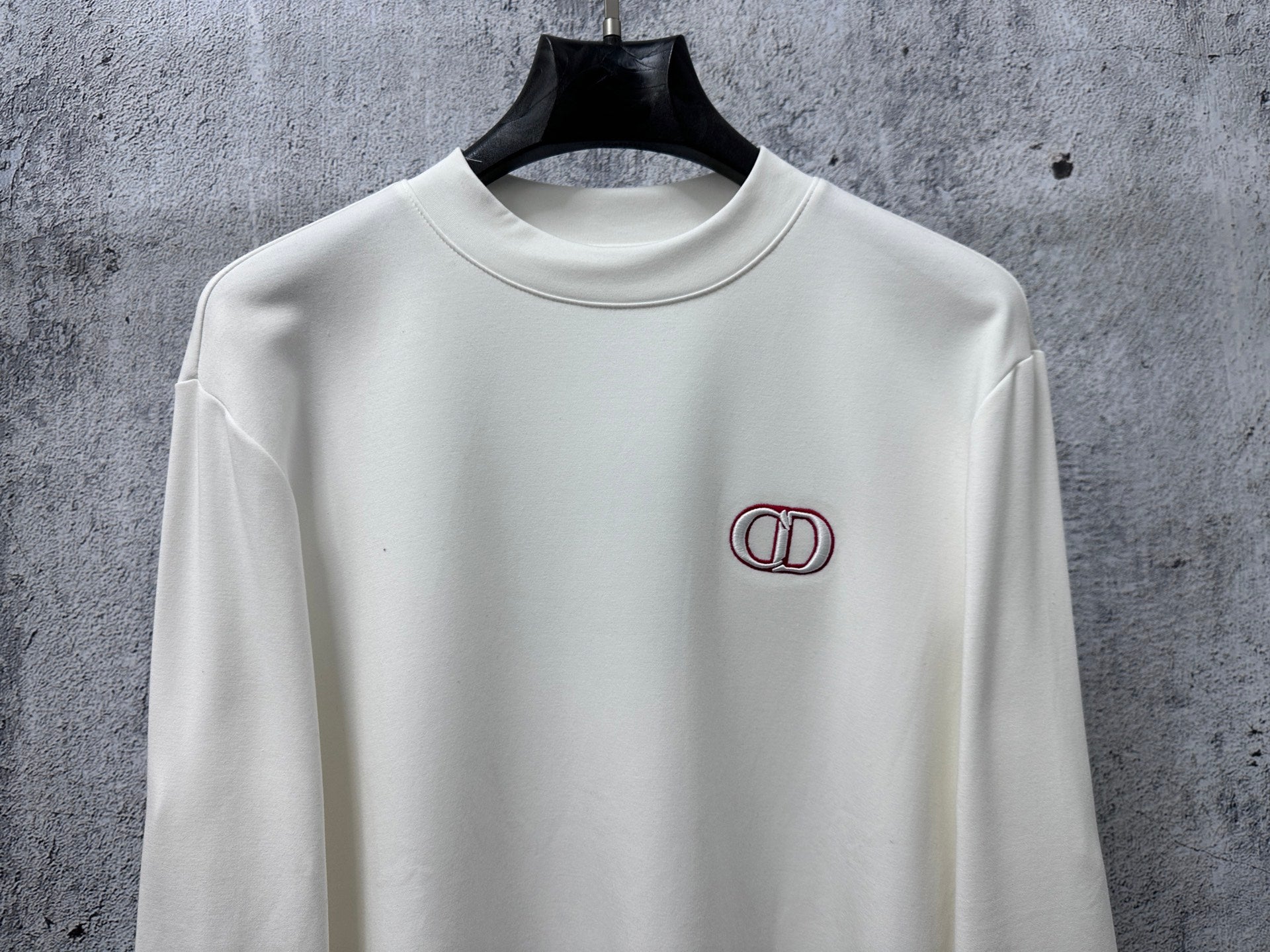 White long-sleeve top with CD logo embroidery at upper chest
