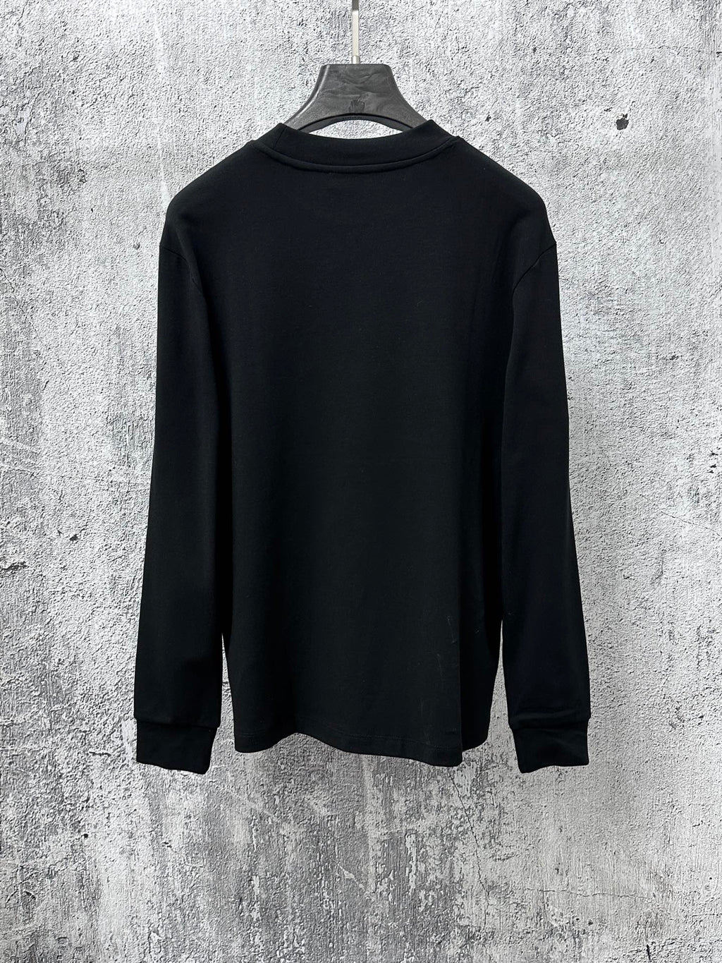 Black long-sleeve sweatshirt back view on hanger