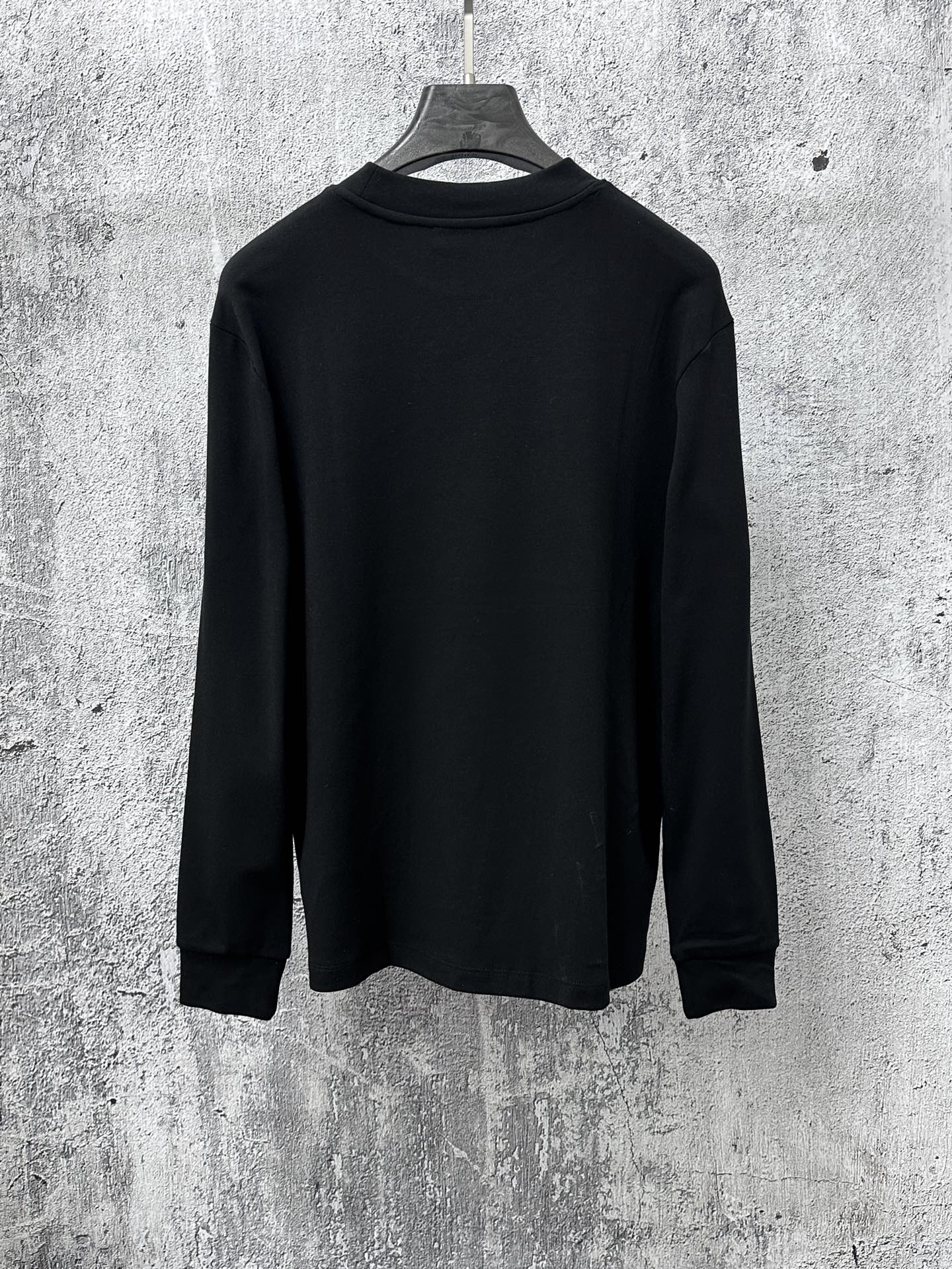 Black long-sleeve sweatshirt back view on hanger