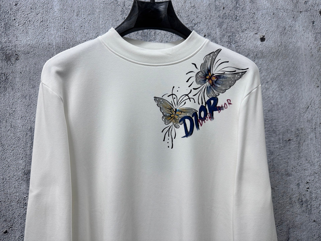 White long-sleeve crew-neck top with Dior floral and butterfly graphic.