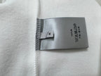 White sweatshirt fabric care label with washing and material icons.