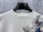 White crew-neck sweatshirt with partial Dior floral print detail.
