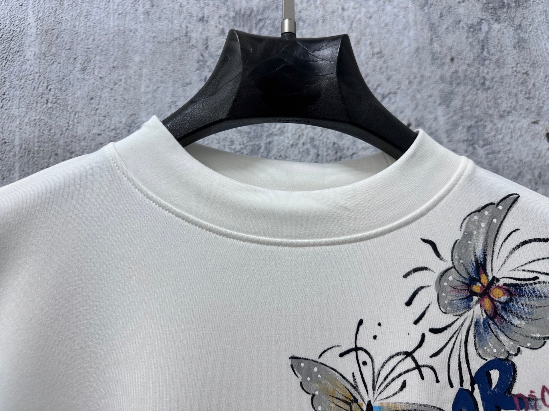 White crew-neck sweatshirt with partial Dior floral print detail.