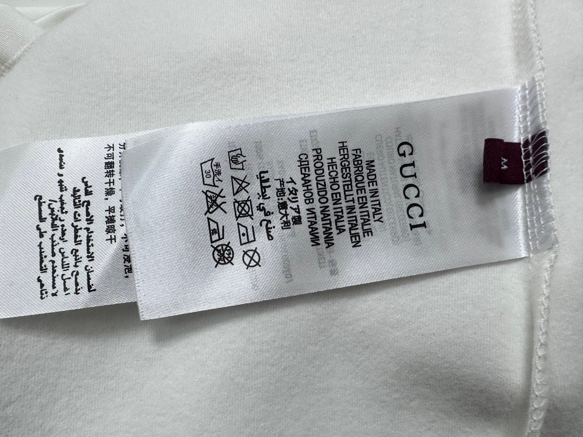 White T-shirt size label and care symbols with Gucci text