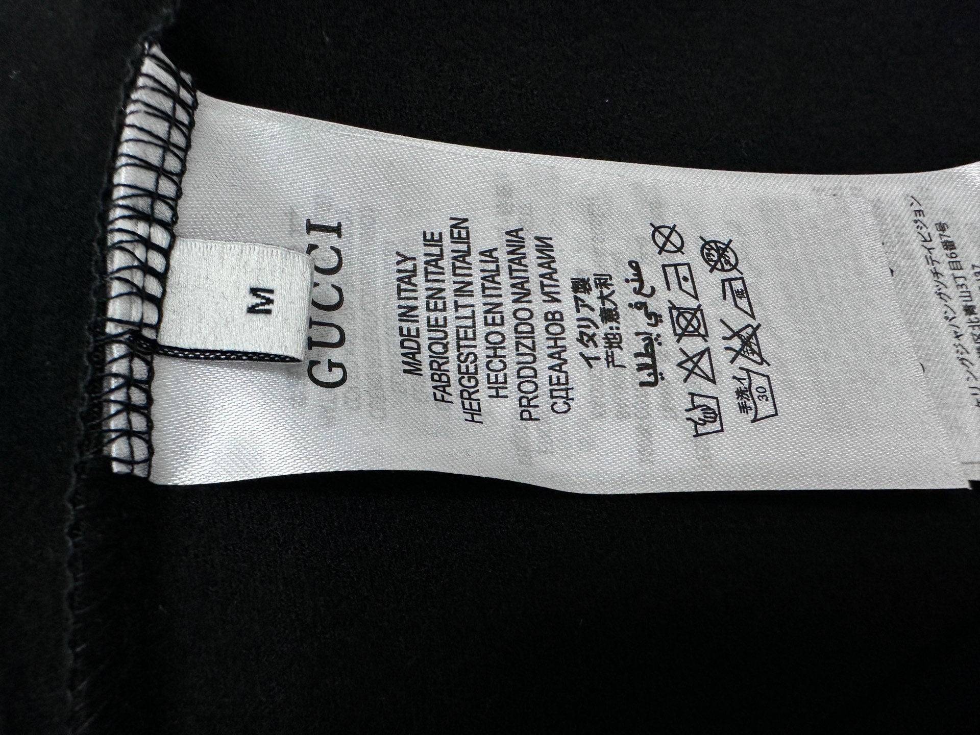 Clothing size label reading M; Gucci and care text inside sweatshirt