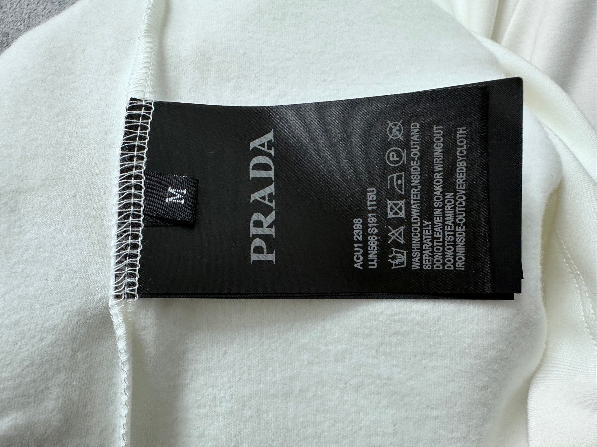White sweatshirt with black PRADA care label tag inside neckline