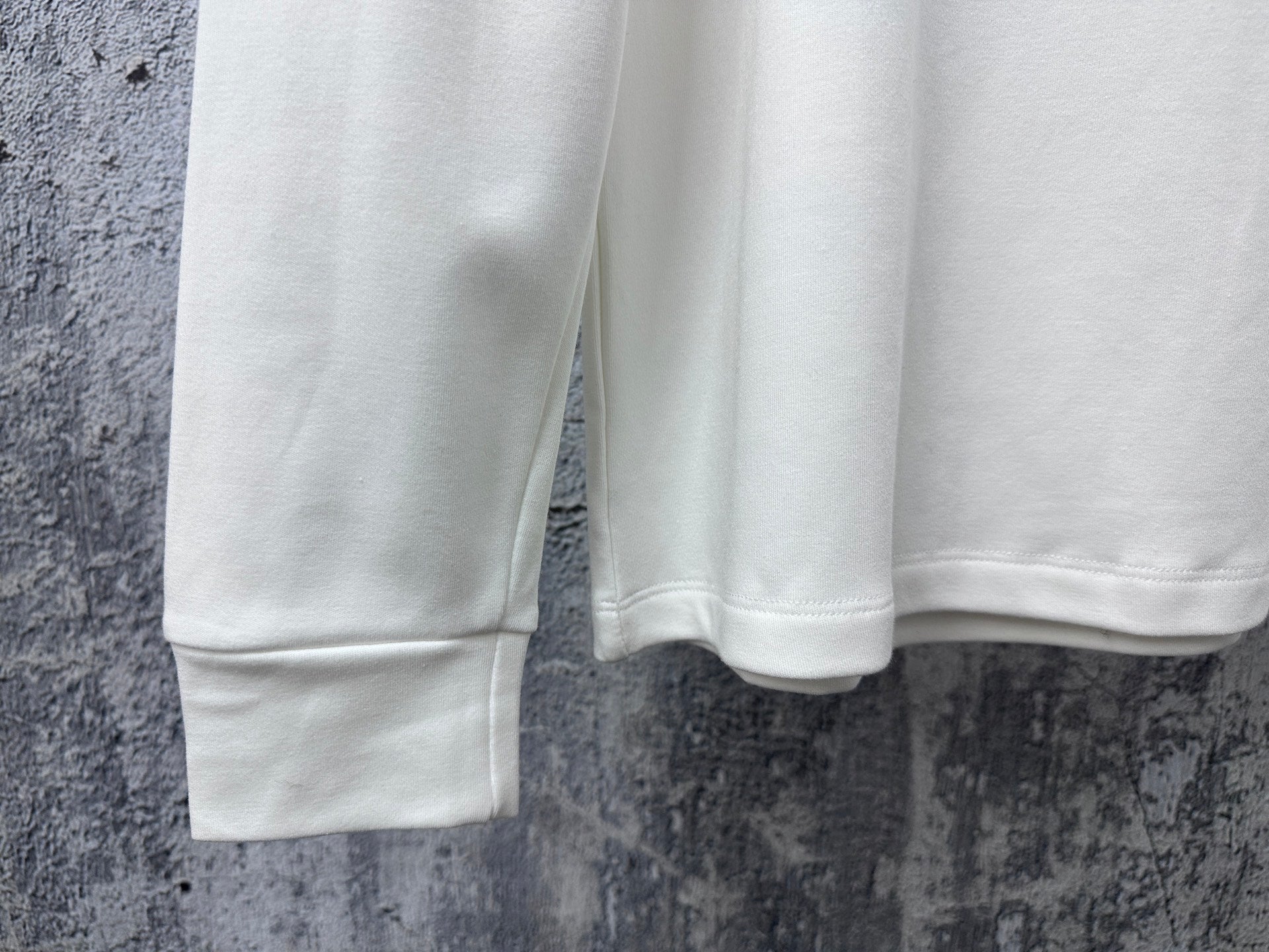 White sweatshirt hem and sleeves, showing ribbed cuffs and bottom edge
