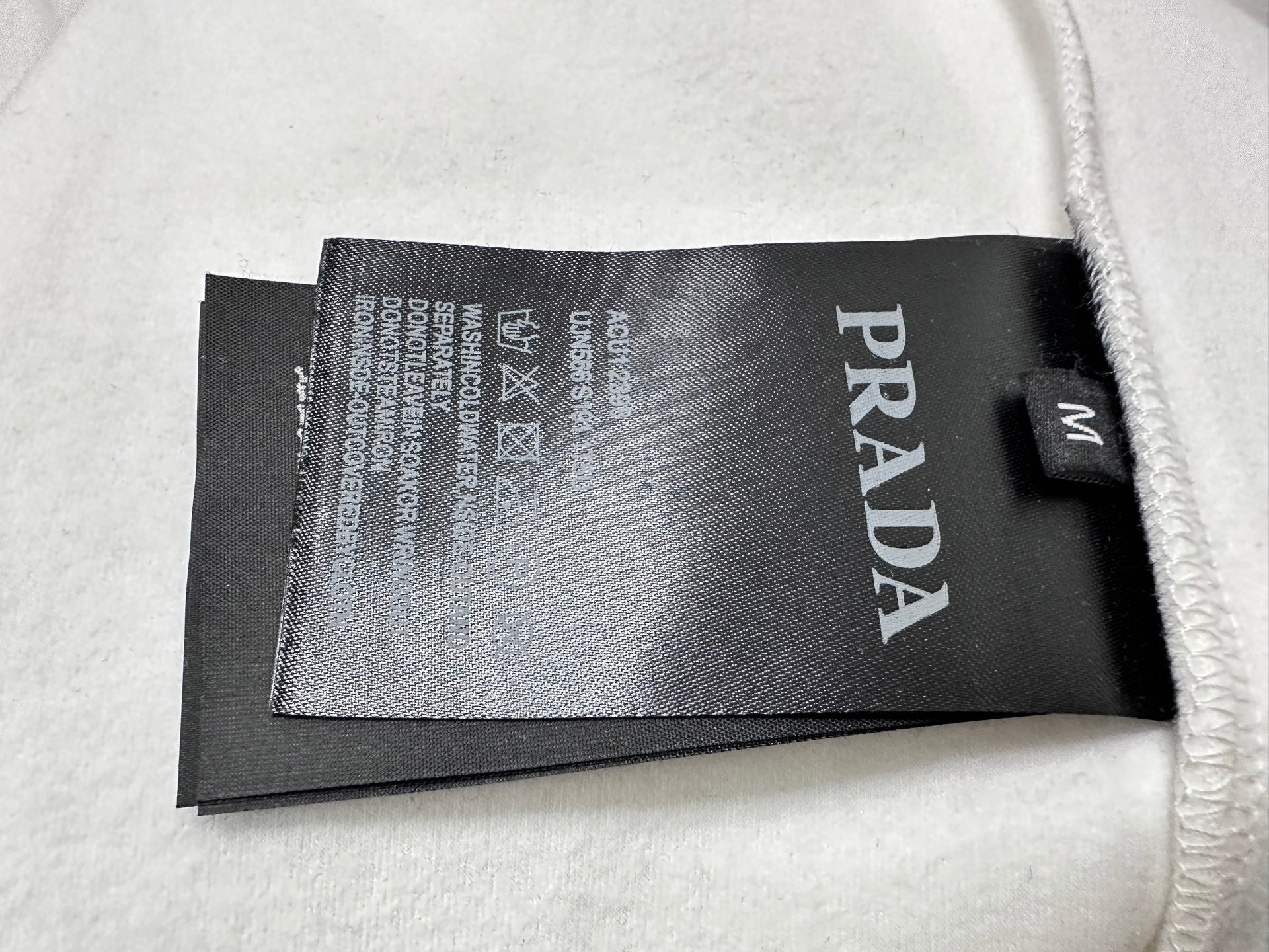 PRADA label tag on inside of cream sweatshirt