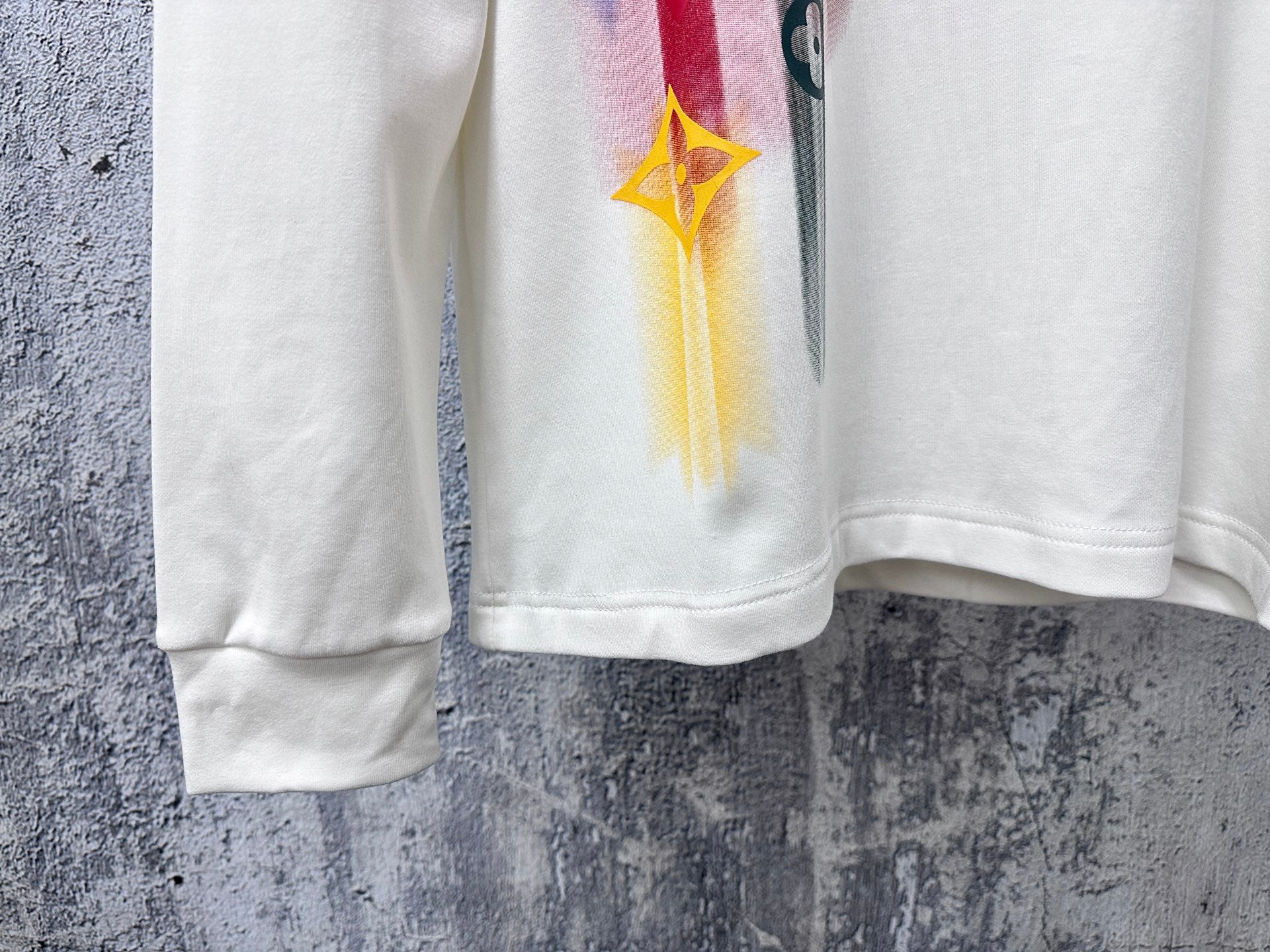 White long-sleeve sweatshirt with colorful graphic on lower sleeve