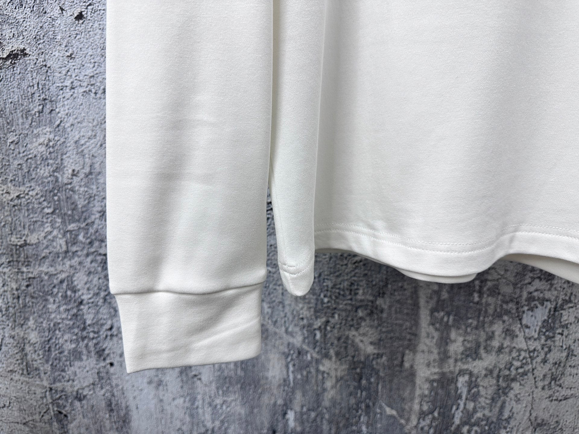 Louis Vuitton white long-sleeve crewneck shirt cropped view of lower front and hem