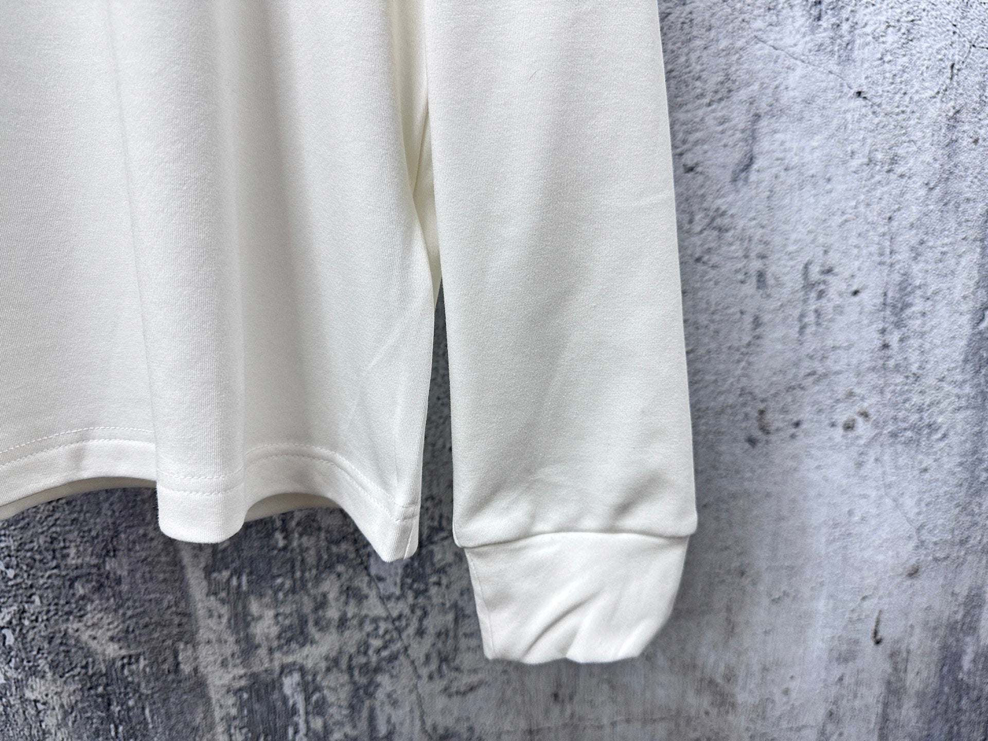 Louis Vuitton white long-sleeve crewneck shirt cropped view of lower torso and sleeves