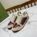 Unisex luxury sneakers by Gucci, cream with burgundy gem-style panels and lace-up.