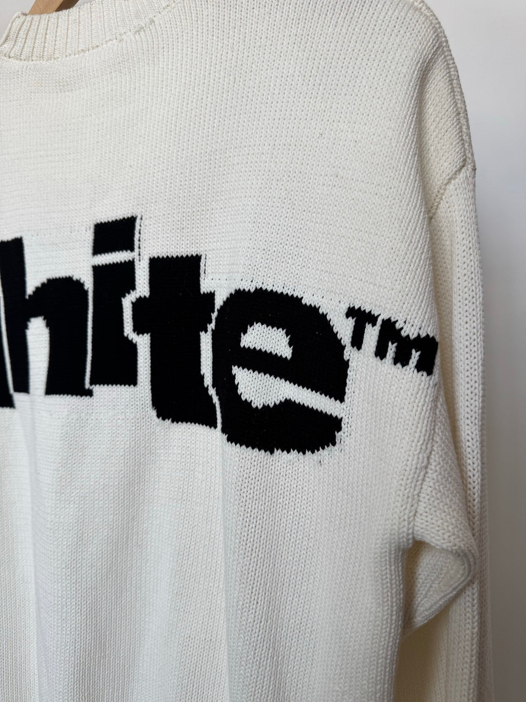 Off-white knit sweater sleeve detail with black logo lettering