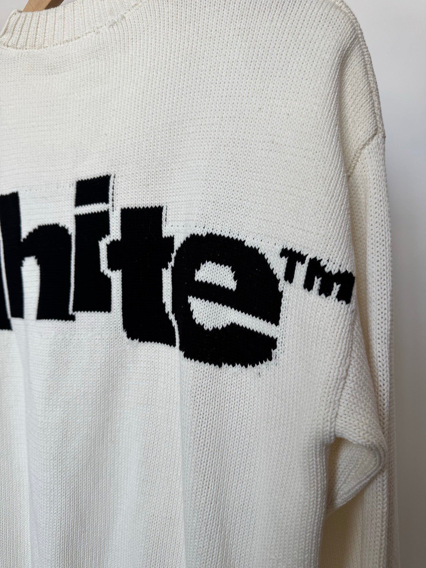 Off-white knit sweater sleeve detail with black logo lettering