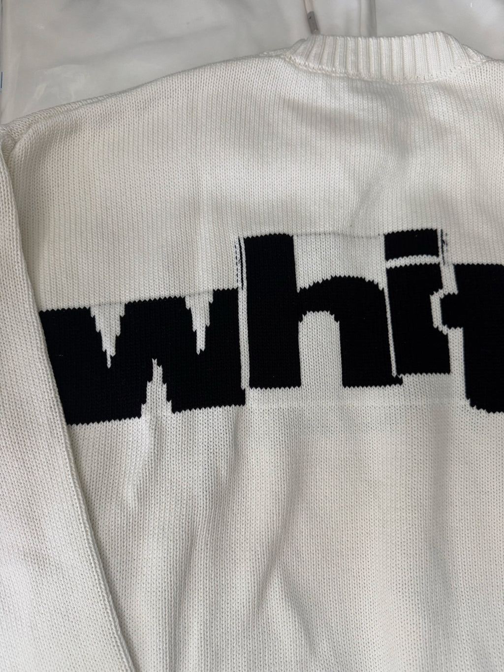 Off-White™ knit sweater back close-up, off-white knit with black "white" logo