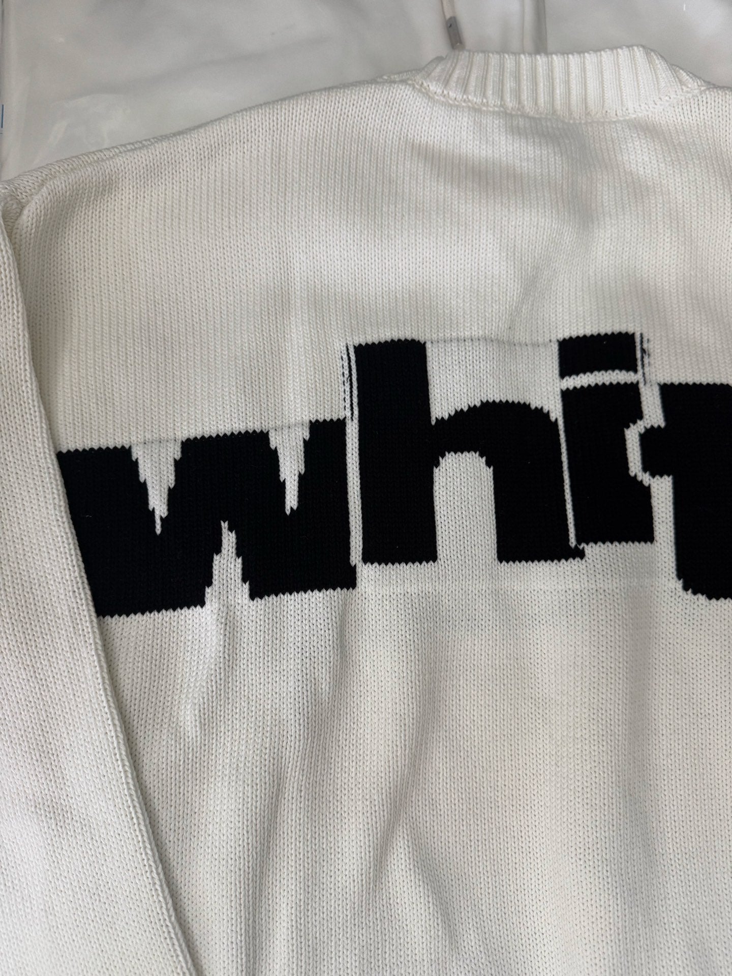 Off-White™ knit sweater back close-up, off-white knit with black "white" logo