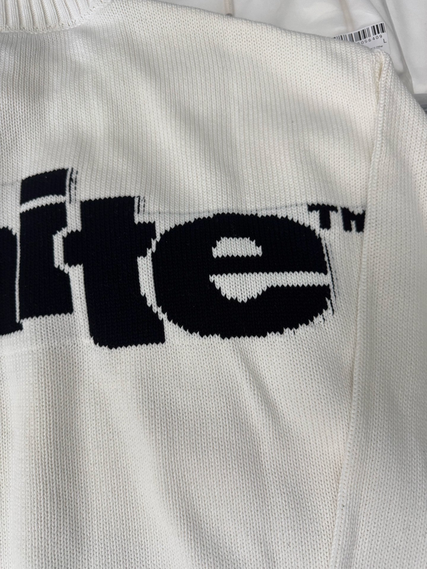 Off-White™ knit sweater back close-up, off-white with black "te" logo text