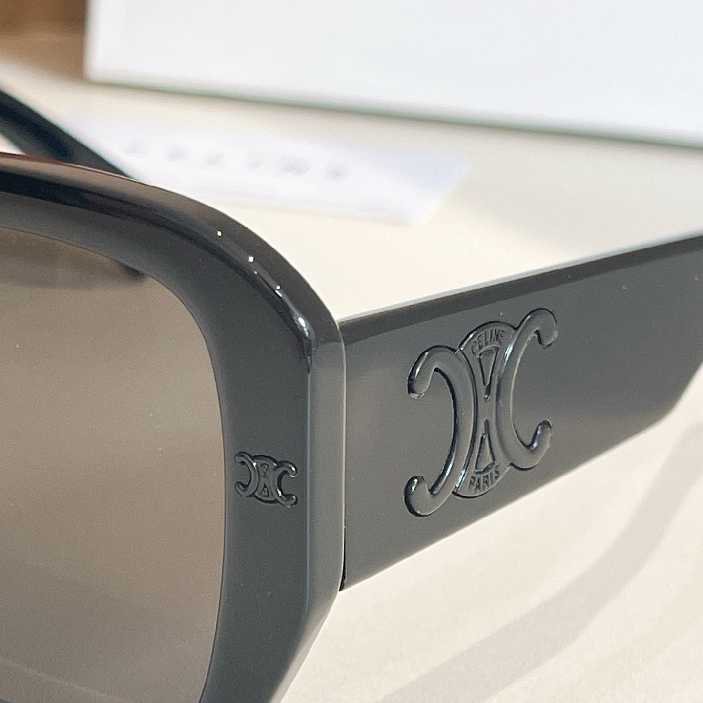 Black sunglass temple arm with embossed monogram detail