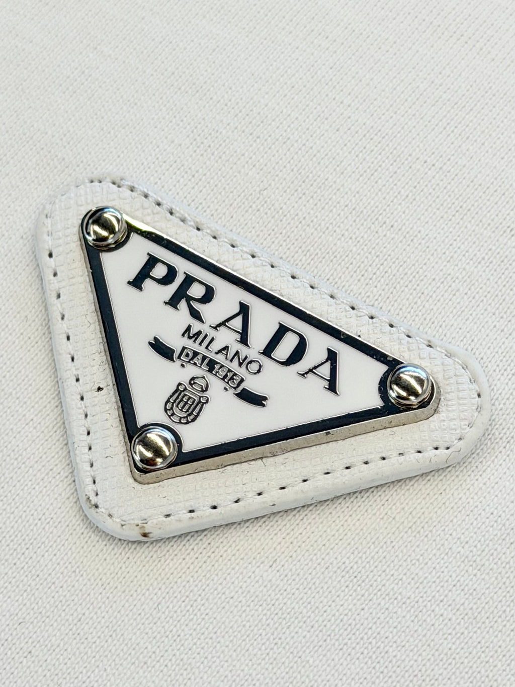 PRADA Milano logo patch with metal eyelets on white fabric