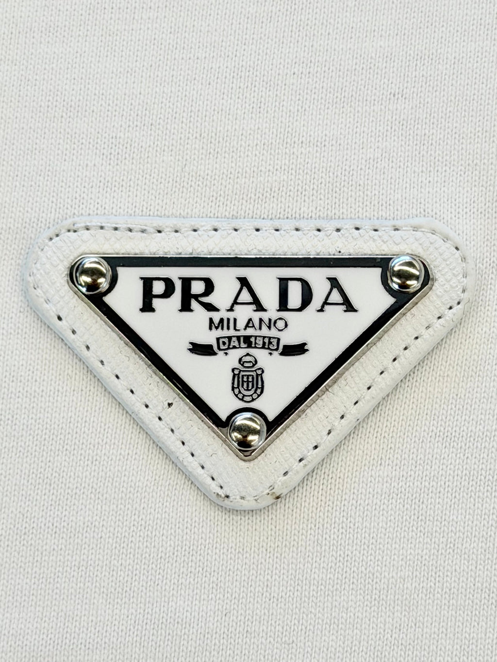 PRADA Milano triangular logo patch on white fabric