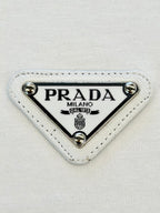 PRADA Milano triangular logo patch on white fabric