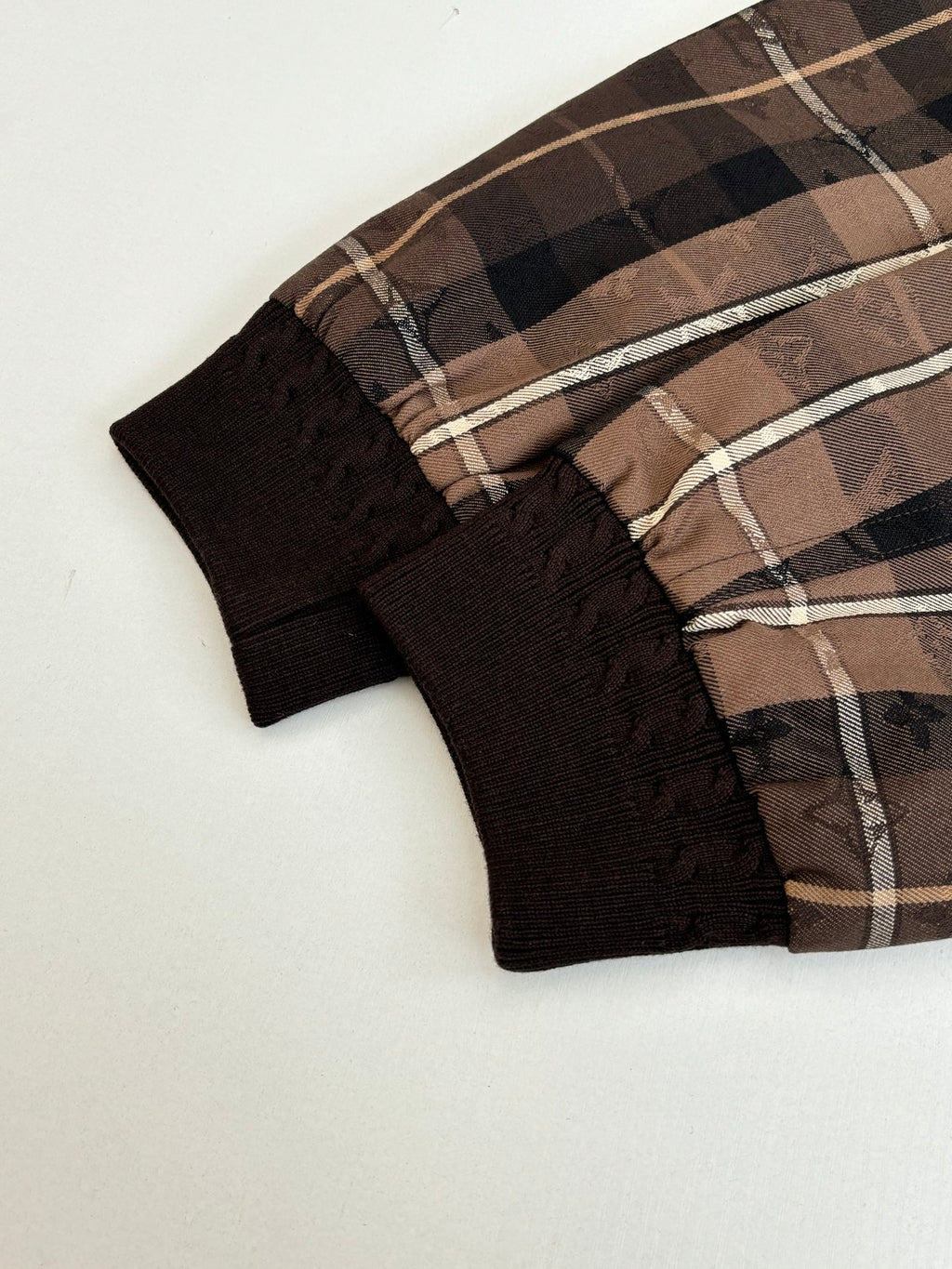 Plaid jacket sleeve ends with black ribbed cuffs and drawstring tabs