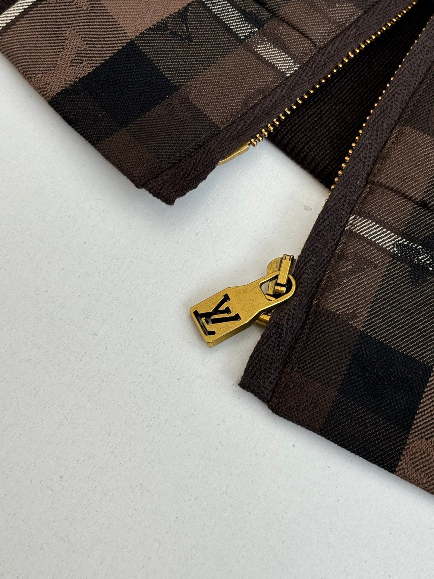 Gold-toned zipper on plaid jacket with logo pull tab
