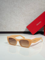 Sunglasses with light tan frames and brown tinted lenses, Prada logo on temple.