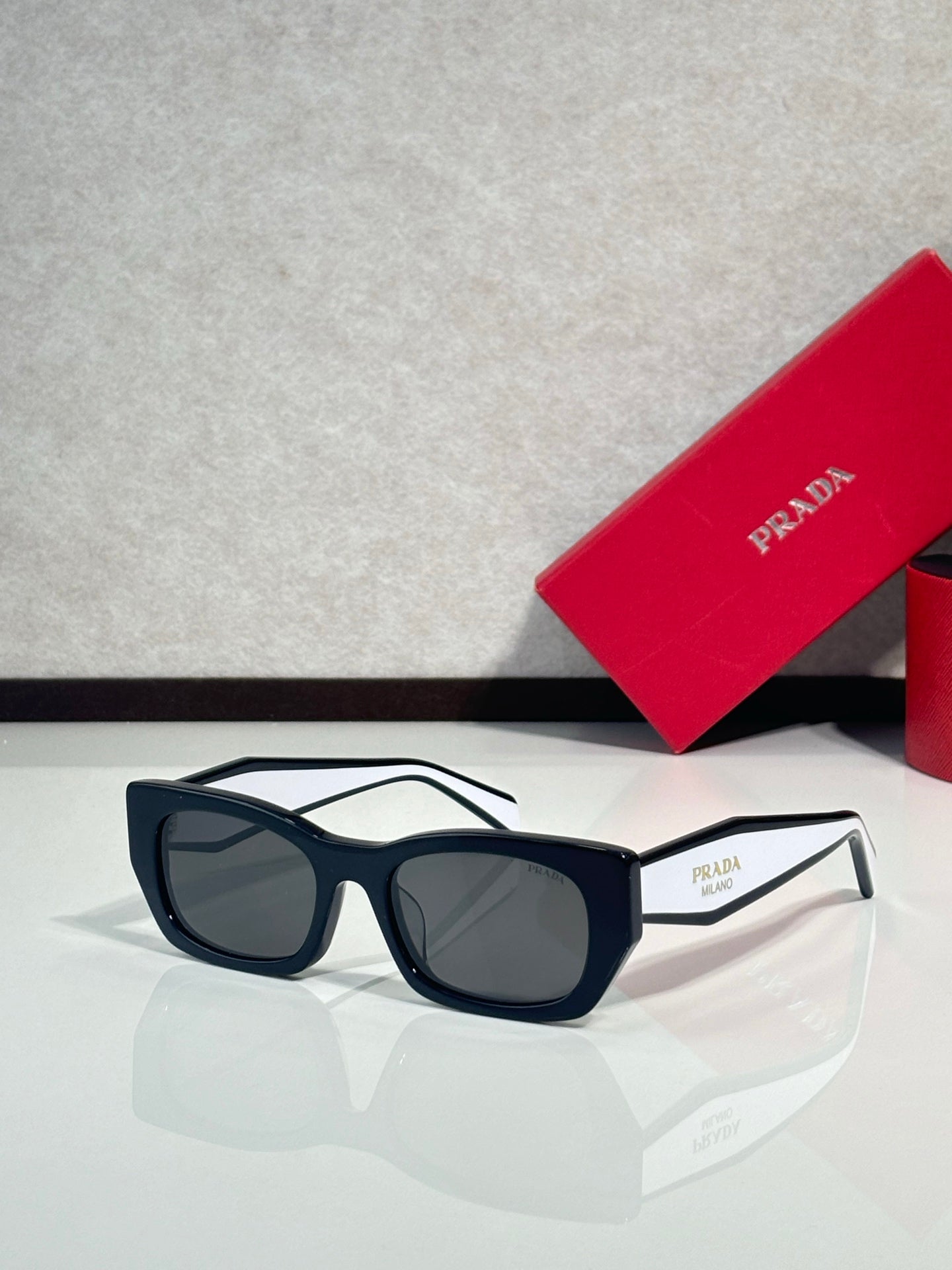 Sunglasses with black frames and dark lenses, Prada logo on temple.