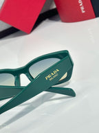 Green sunglasses temple with Prada Milano logo and angled hinge detail.