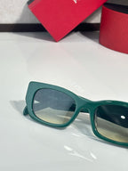 Green sunglasses with translucent frames and large lenses, Prada logo on temple.