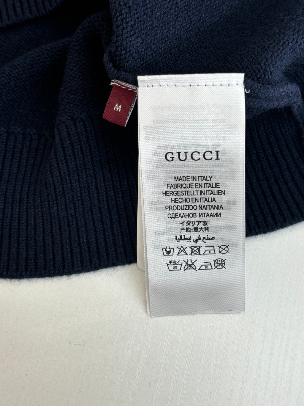 Clothing size and care tag on navy knit sweater with Gucci branding