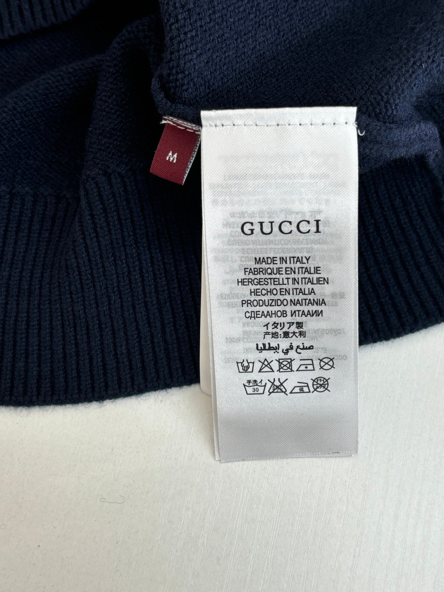 Clothing size and care tag on navy knit sweater with Gucci branding
