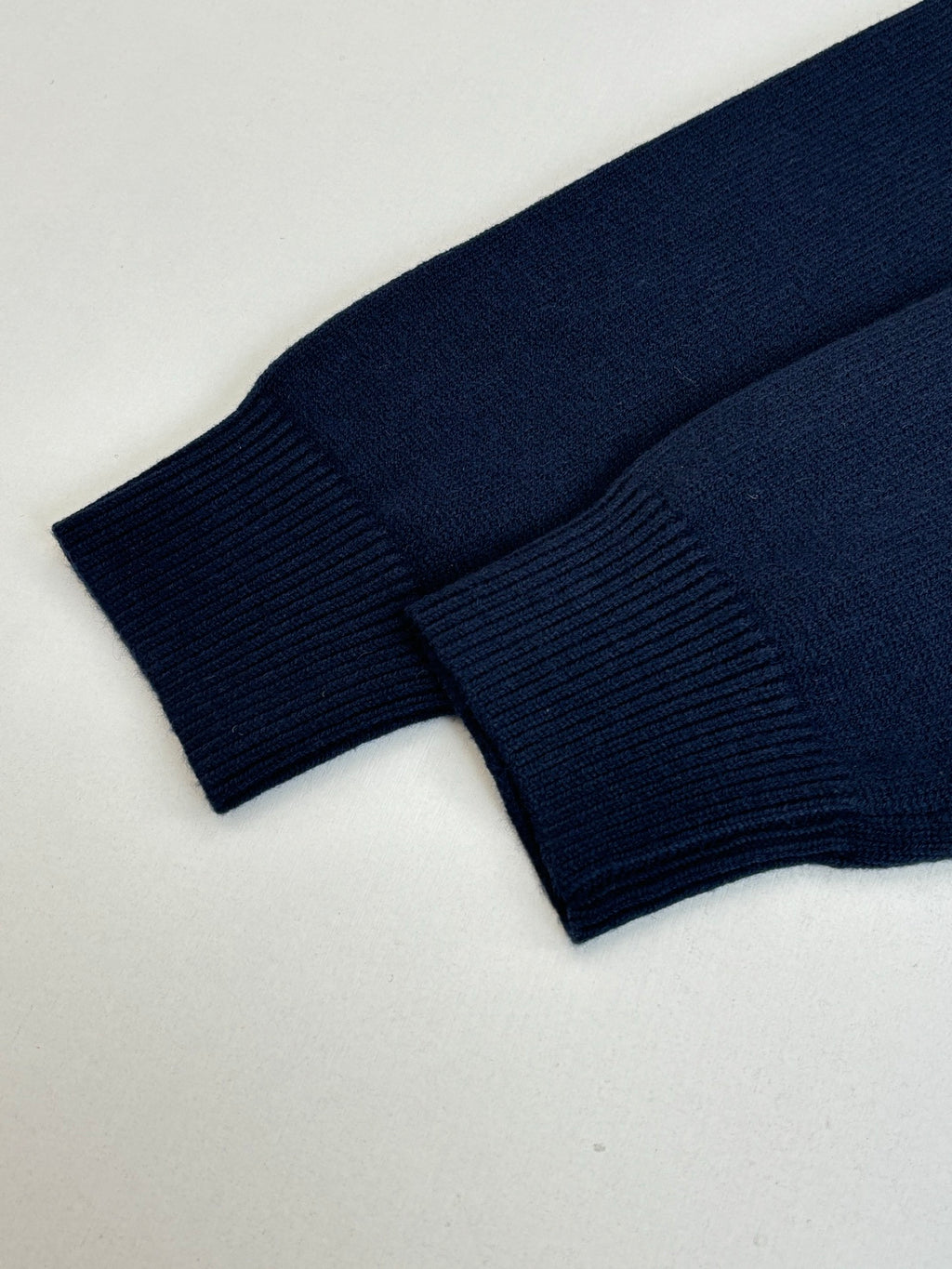 Navy knit sweater close-up of ribbed cuffs and lower hem