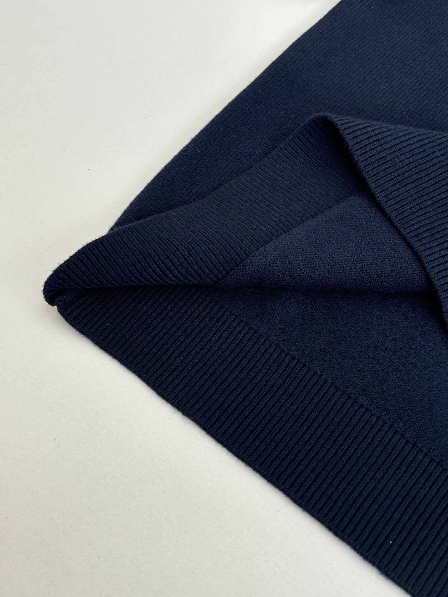 Navy knit sweater close-up of collar seam and ribbed sleeve cuff