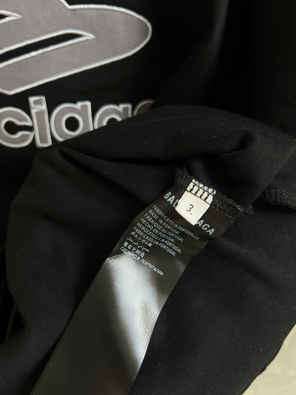 Black T-shirt fabric close-up with care label near collar seam