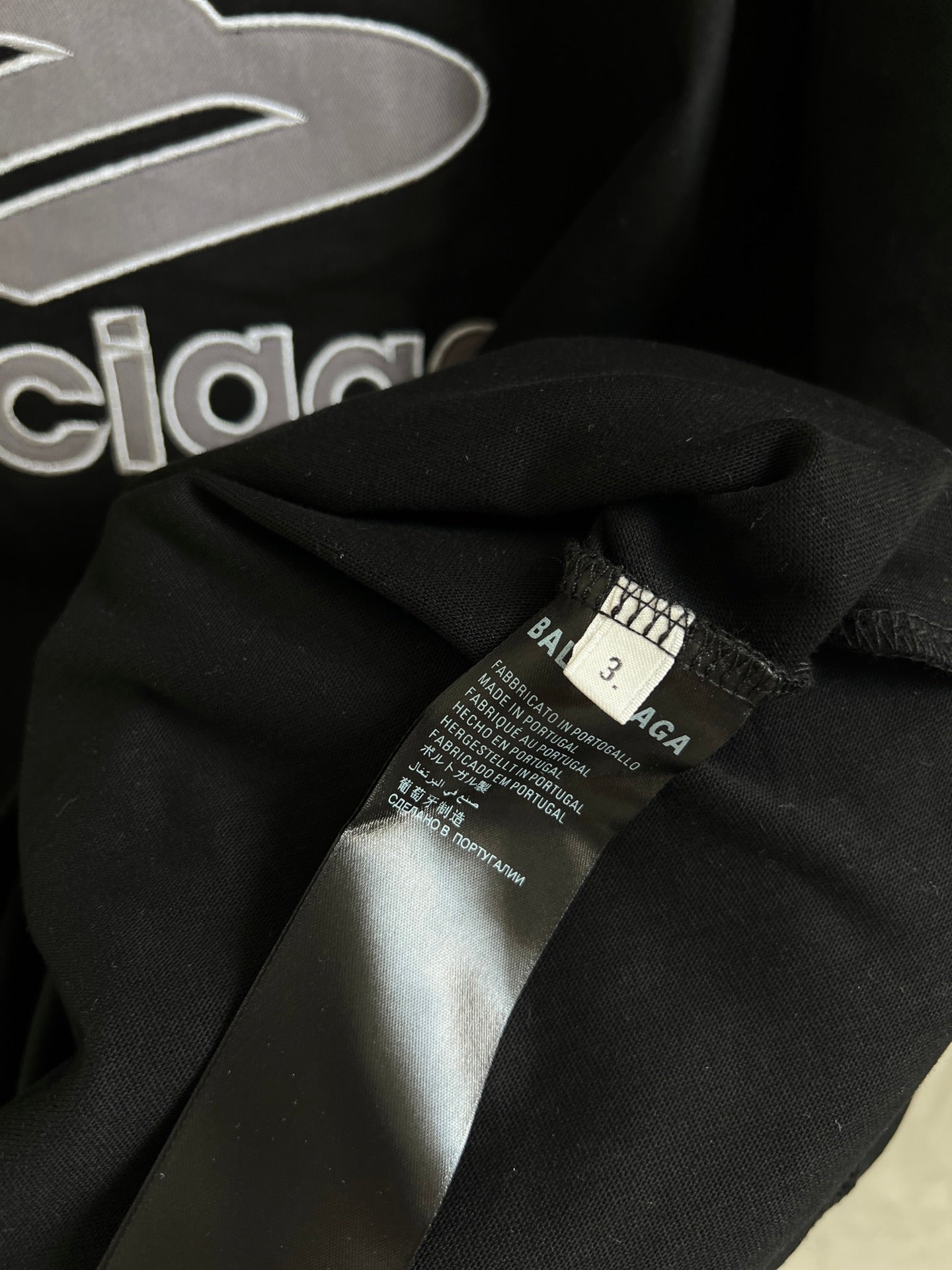 Black T-shirt fabric close-up with care label near collar seam