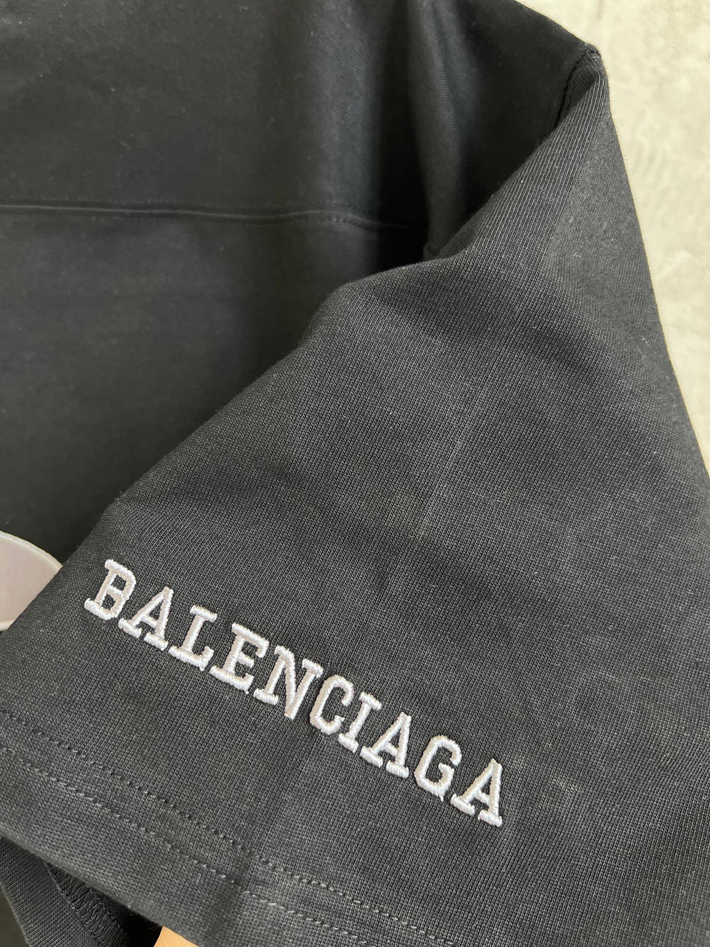 Black T-shirt sleeve with Balenciaga text embroidery along cuff