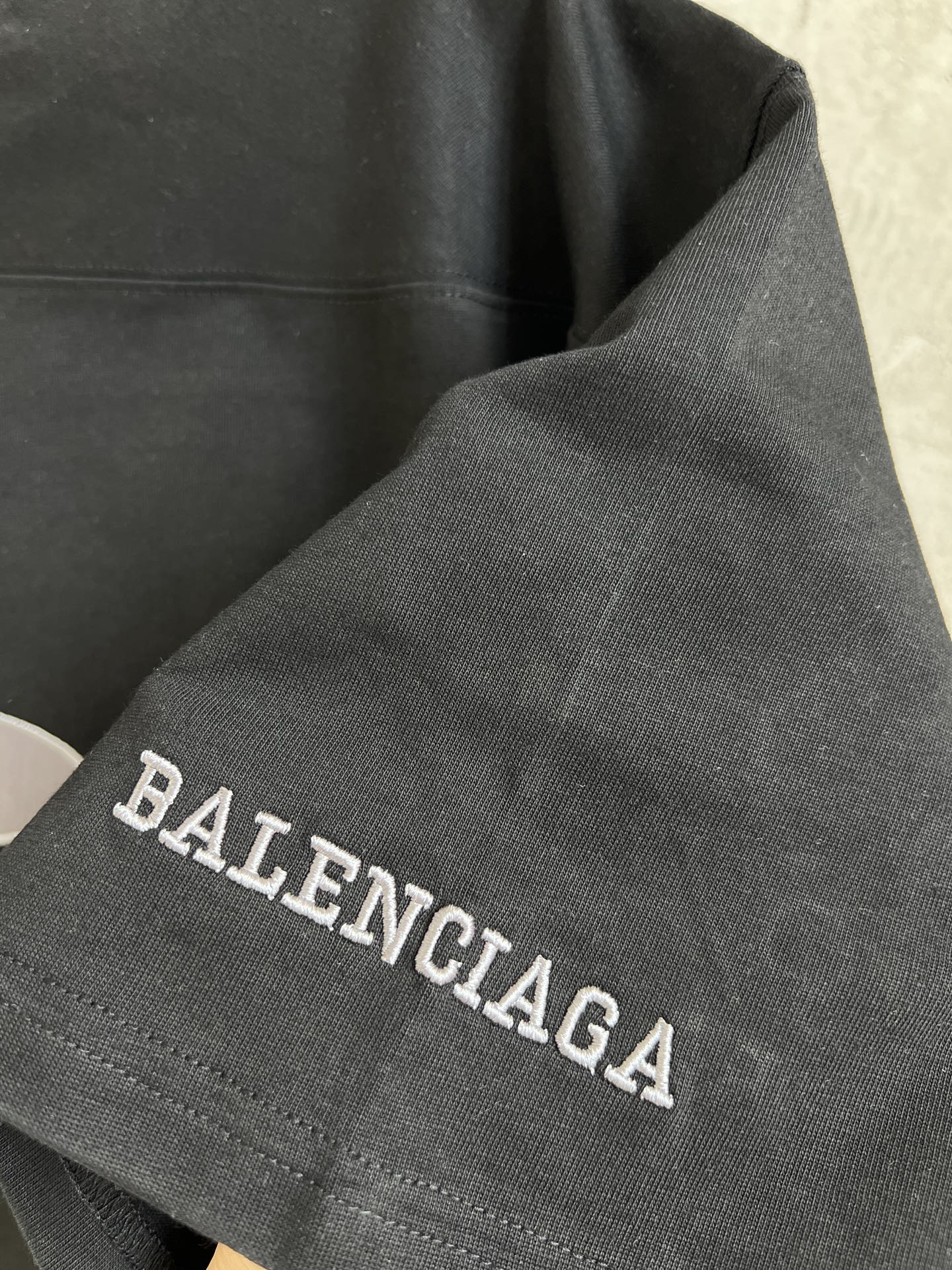Black T-shirt sleeve with Balenciaga text embroidery along cuff